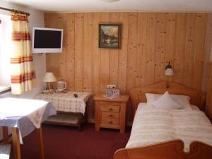 a bedroom with a bed and a tv on the wall at Pension Herzoghäusel in Bischofswiesen