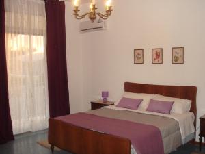 a bedroom with a bed with purple pillows and a window at Appartamento Raggio Di Sole in Acireale