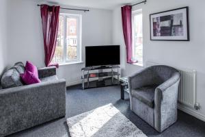 een woonkamer met 2 stoelen en een flatscreen-tv bij Watkins House by Cliftonvalley Apartments in Cardiff