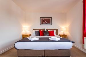 a bedroom with a large bed with red pillows at Watkins House by Cliftonvalley Apartments in Cardiff