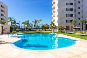 a swimming pool in a resort with palm trees and a building at Apartamento Playa Marinsa in Torre del Mar