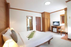 a bedroom with a white bed and a television at Palmyra Patong Resort Phuket - SHA Extra Plus in Patong Beach