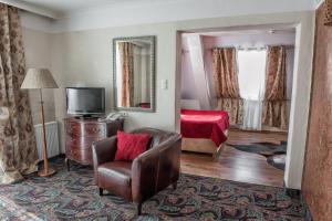 a room with a chair and a television and a bed at Hotel Lipowy Most in Supraśl