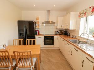 a kitchen with a wooden table and a black refrigerator at Llain Bach in Llangefni +13 photos