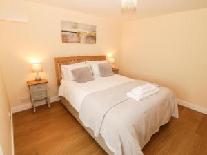 1 dormitorio con 1 cama con sábanas blancas y 2 lámparas en Llain Mai, en Llangefni
