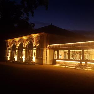 un bâtiment éclairé la nuit avec des bancs devant dans l'établissement ORANGERIE de CHATEL-Selection FIGARO & ELLE Magazine, à Cleppé