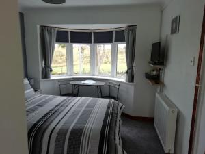 a bedroom with a bed and a table and a window at Rockville Amlwch LL68 0TE, UK Apartment in Llanfflewyn