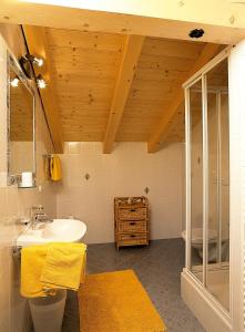 a bathroom with a white sink and a wooden ceiling at Fassnauerhof Ridnaun in Racines