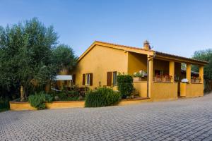 uma casa amarela com uma entrada de tijolos em frente em Villa Elisabetta em Trequanda