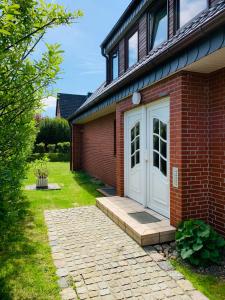 a red brick house with a white door at Ferienwohnung Syltliebe in Wenningstedt