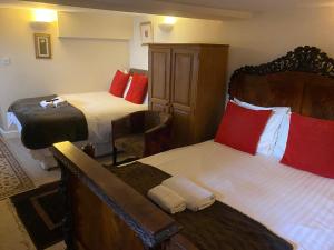 a hotel room with two beds with red pillows at The Old Court Hotel in Witney