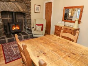 een woonkamer met een houten tafel en een open haard bij Nutkin Cottage in Windermere