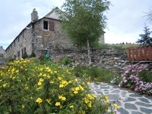 an old stone building with a garden with yellow flowers at Gite Le Francillon in Les Estables