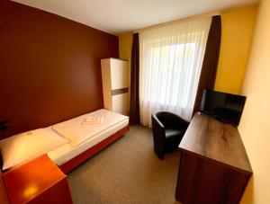 AltenmedingenにあるAdamidis Hotelのベッドルーム(ベッド1台、椅子、テレビ付)