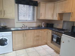 a kitchen with wooden cabinets and a washer and dryer at Library Square Penthouse in Belfast