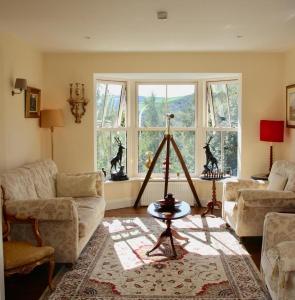 a living room with a couch and a table and windows at Heather House in Laragh
