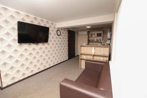 a living room with a couch and a tv on a wall at Hotel Capri in Sukhum