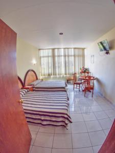 um quarto com duas camas e uma mesa com cadeiras em Hotel Plaza Sahuayo em Sahuayo de José María Morelos