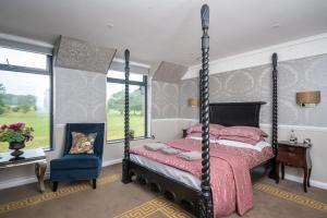 ein Schlafzimmer mit einem Himmelbett und einem Stuhl in der Unterkunft Guildford Manor Hotel & Spa in Guildford