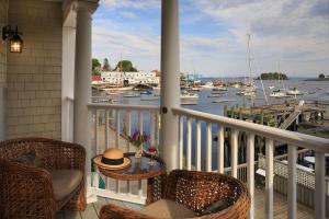 a balcony with chairs and a table and boats in the water at Grand Harbor Inn in Camden