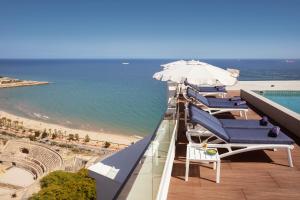 a row of chairs and umbrellas on a balcony overlooking the ocean at H10 Imperial Tarraco 4 Sup in Tarragona