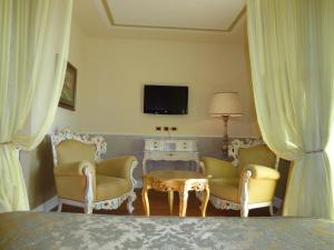 una camera da letto con due sedie, un tavolo e una TV di Hotel Confine a Colà