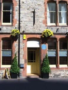 a brick building with a yellow door and two plants at The Lounge Hotel & Bar in Penrith