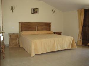 a bedroom with a large bed with a wooden headboard at Hotel Las Fuentes in Torrecaballeros