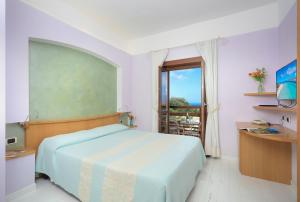 a bedroom with a large bed and a balcony at Hotel Cala Reale in Stintino