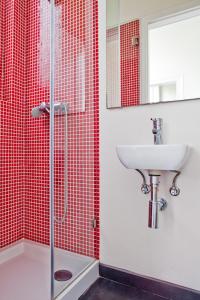 ein rot gefliestes Bad mit einem Waschbecken und einer Dusche in der Unterkunft Gulbenkian in Lissabon