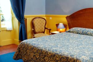 sypialnia z łóżkiem, krzesłem i lampką w obiekcie Hôtel Colombet w mieście Nyons