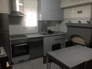 uma cozinha com uma mesa, uma pia e um fogo em Casa Porta de Santiago em Pinhel