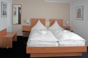 a bedroom with a large white bed with a wooden headboard at Hotel Restaurant Vogt in Rietberg