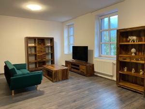 uma sala de estar com uma televisão, um sofá e uma cadeira em Boutique Apartments Liberec em Liberec