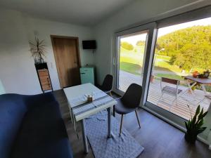 ein Wohnzimmer mit einem Tisch und Stühlen sowie einem großen Fenster in der Unterkunft Ferienwohnung Karussell in Siebenbach