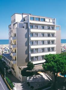 a tall white building next to the ocean at National Hotel in Rimini