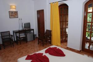 a bedroom with a bed and a desk and a television at Sea Breeze Beach Resort Candolim, Goa in Candolim