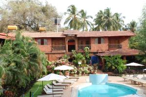 un complejo con piscina, sillas y un edificio en Sea Breeze Beach Resort Candolim, Goa, en Candolim