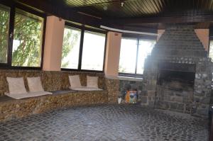 a living room with a stone fireplace and windows at Garden Vendégház Makó in Makó