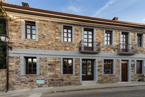 a brick building with windows on a street at Posada Sierra de la Culebra in Ferreras de Abajo