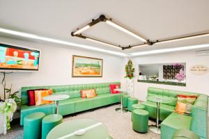una sala de espera con un sofá verde y mesas en Hotel Amalfi, en Bellaria-Igea Marina