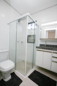 uma casa de banho com um WC e uma cabina de duche em vidro. em Flats Andira Kuss em Sinop