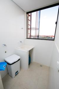 uma casa de banho com um lavatório, um WC e uma janela. em Flats Andira Kuss em Sinop