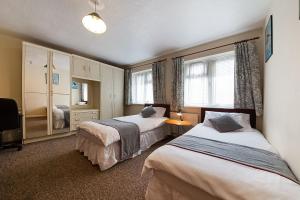 a hotel room with two beds and a television at OYO Honeycroft Lodge in Uxbridge