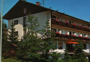 ein großes weißes Gebäude mit Blumen auf den Balkonen in der Unterkunft Hotel Reichmann in Sankt Kanzian am Klopeiner See