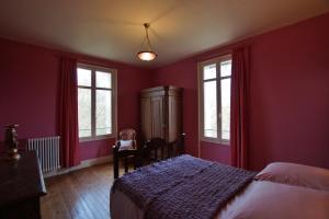 una camera da letto con pareti rosse, un letto e finestre di Petit château Le Piot a Fleurance