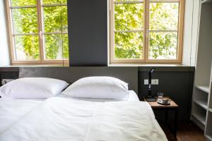 um quarto com uma cama com duas almofadas e duas janelas em Hotel Restaurant Joseph em Bruckneudorf