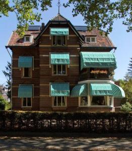 een groot huis met groene luifels erop bij B&B Villa Anna, Venlo in Venlo