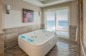 a white tub in a bathroom with a view of the ocean at Xanadu Island in Akyarlar