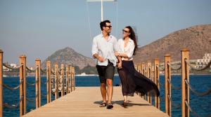 a man and a woman walking on a dock at Xanadu Island in Akyarlar